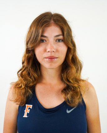 A woman with brown curly hair wears a California State Fullerton sports uniform.